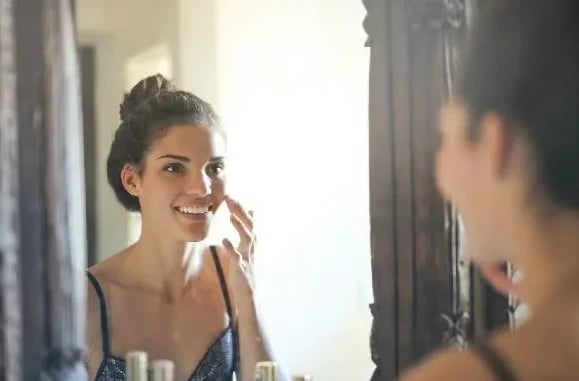 Woman reviewing her facelift results in the mirror during recovery