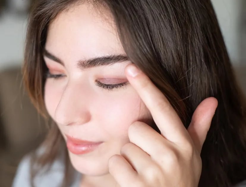 Woman touching the skin beside her eye, the hooding and puffiness patients notice first