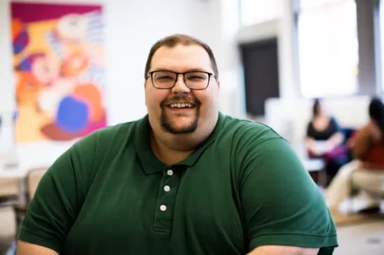 Smiling man with glasses and a goatee in a green polo shirt